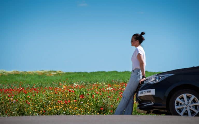 Ani mit unserem Mietwagen vor blühender Landschaft in Marokko im Frühling, Roadtrip Naturkulisse