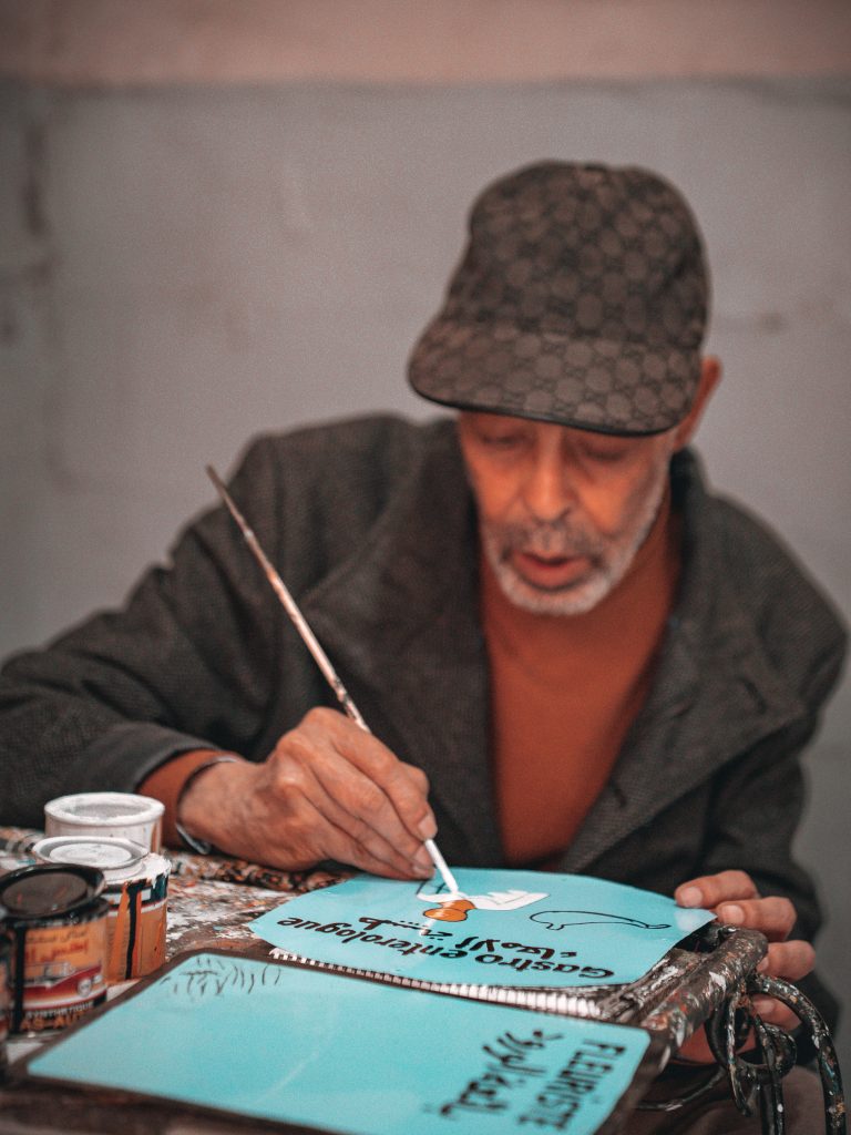 Handwerker bemalt Schilder in den Souks von Marrakesch